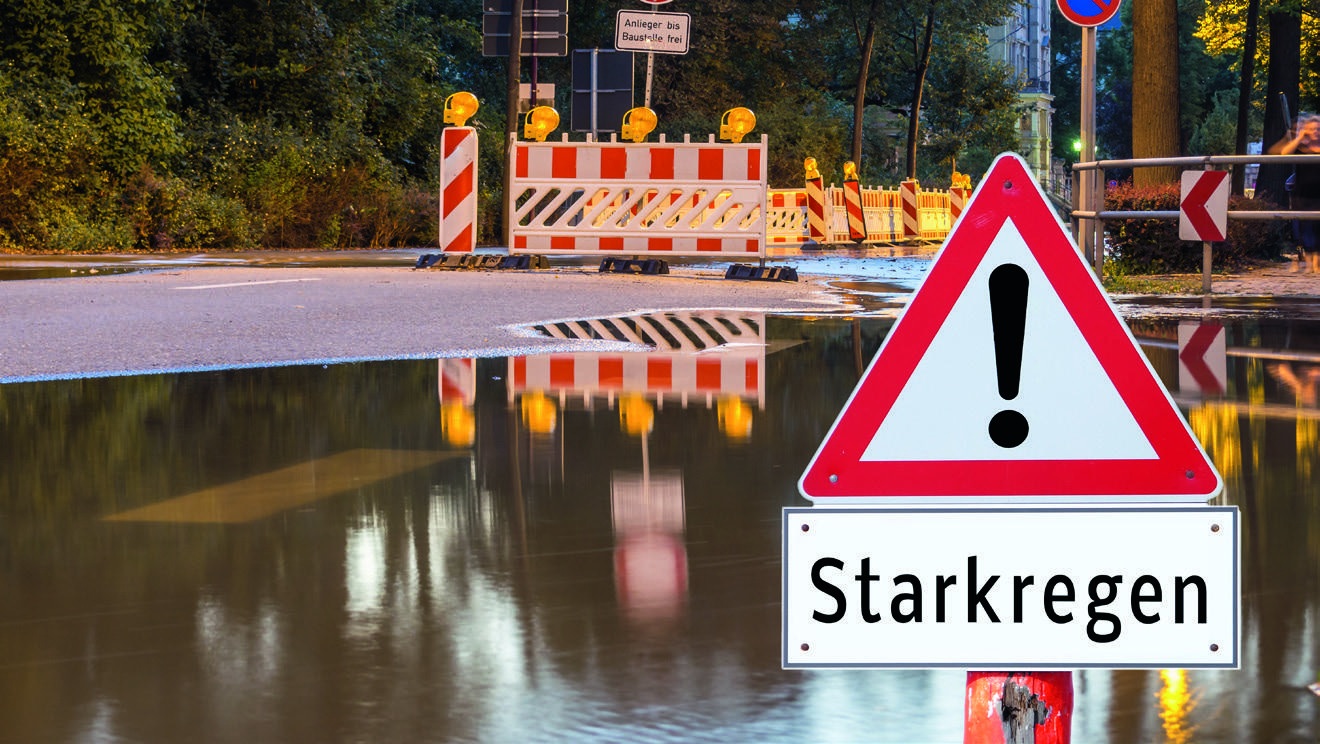 Warnschild vor einer überfluteten Straße nach Starkregen