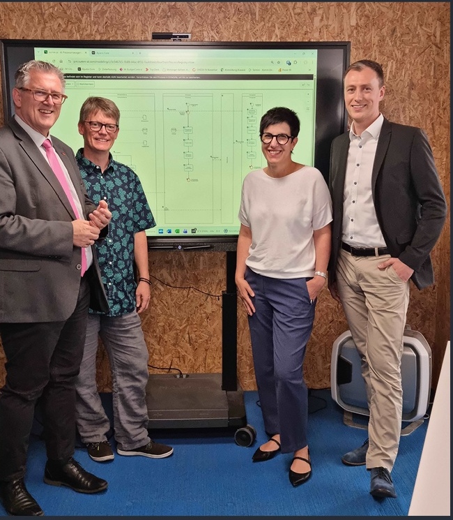 Vertreterinnen und Vertreter der Stadt Metzingen vor einem digitalen Prozessmodell
