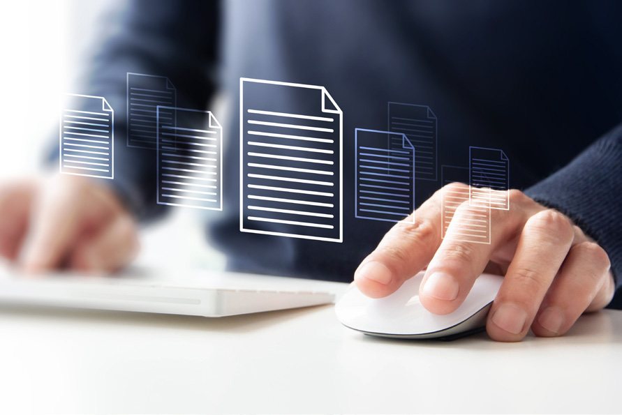 Hand an einer Computermaus vor digital dargestellten Dokumenten