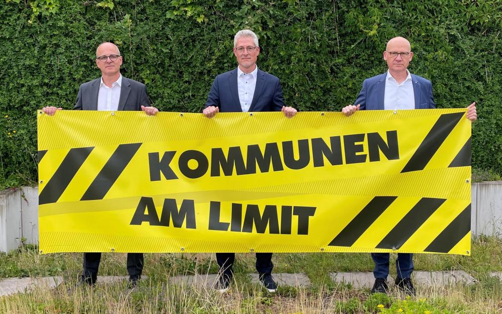 Die drei kommunalen Landesverbände werben mit dem Banner „Kommunen am Limit“ für den bundesweiten Aktionstag am 22. Juni: Alexis von Komorowski (Landkreistag), Steffen Jäger (Gemeindetag) und Ralf Broß (Städtetag, von links).